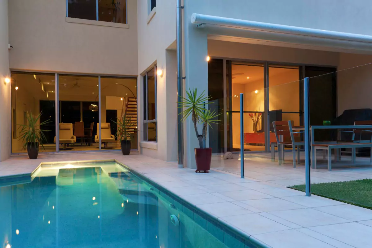 A backyard pool beside a modern home at dusk