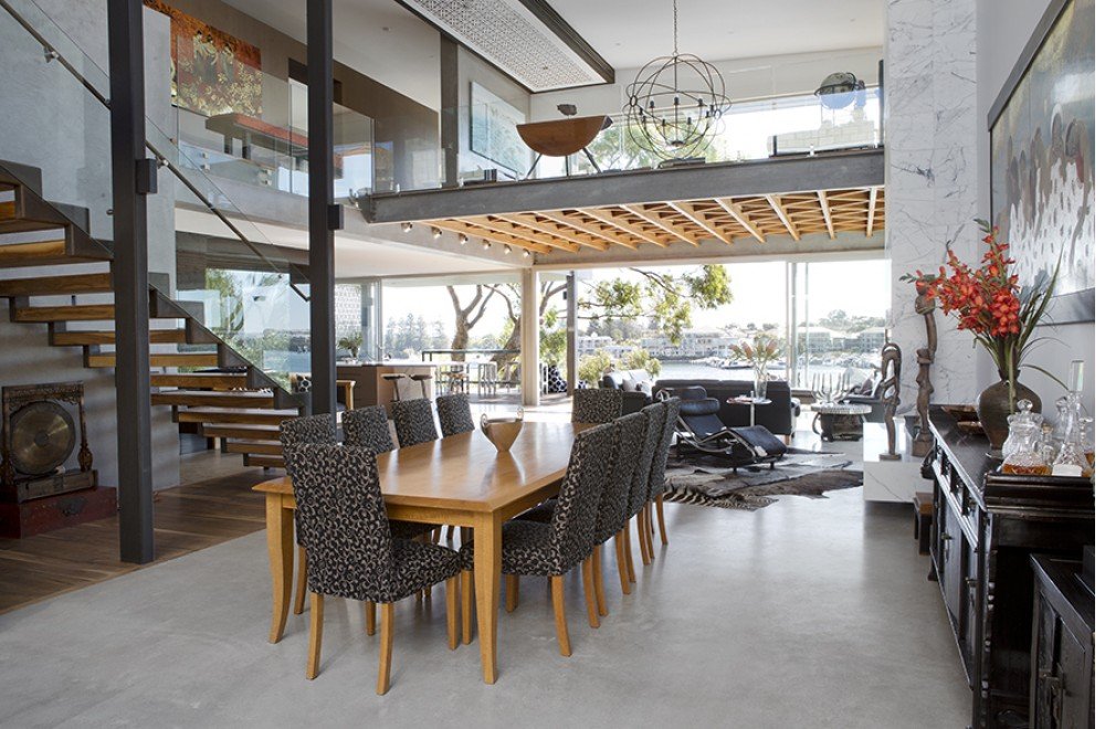 Dining area with polished concrete floor, double-height space and water view through full-height glazing, East Fremantle whole-home hydronic system