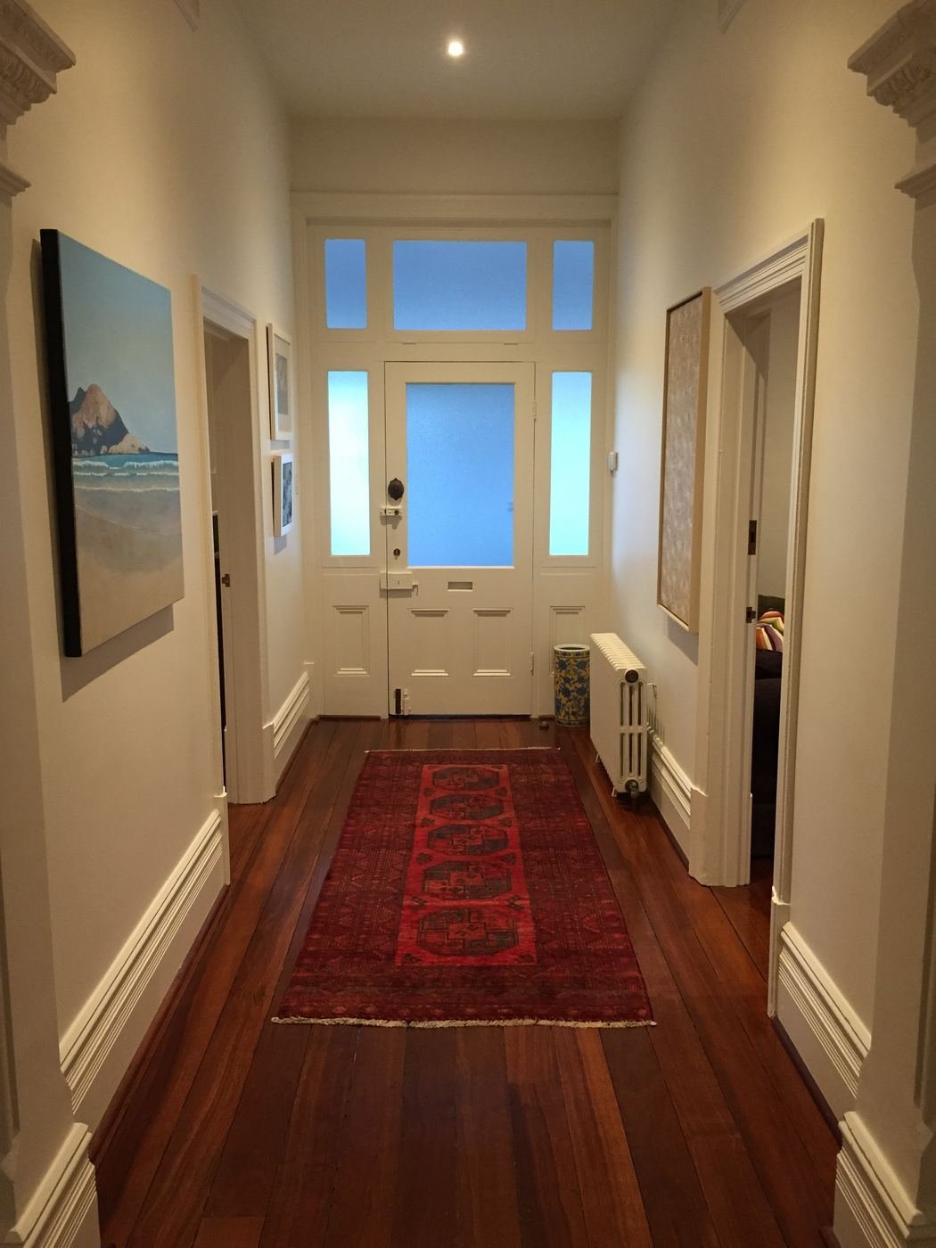A white column radiator beside the front door in the hallway of a character Perth home, with timber floors and ornate cornices